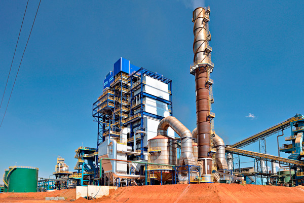 Vista de uma fábrica, com caldeira industrial e outras instalações.