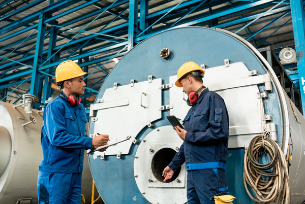 Profissionais inspecionando caldeira industrial em usina.