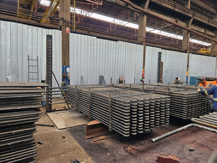 Montagem de economizador de caldeira em f&aacute;brica, mostrando serpentina tubular respons&aacute;vel por aumentar a efici&ecirc;ncia energ&eacute;tica do sistema.