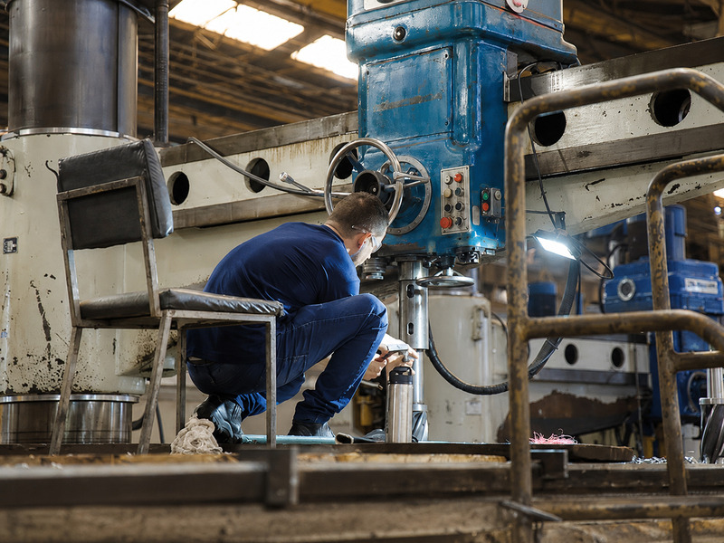 Técnico realizando ajuste em máquina de usinagem pesada durante manutenção em ambiente industrial.